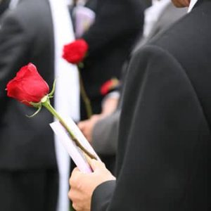 Man holding a rose at a funeral.