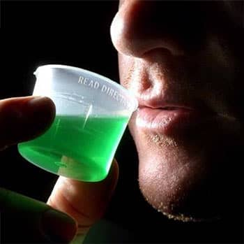 Man drinking a green liquid.