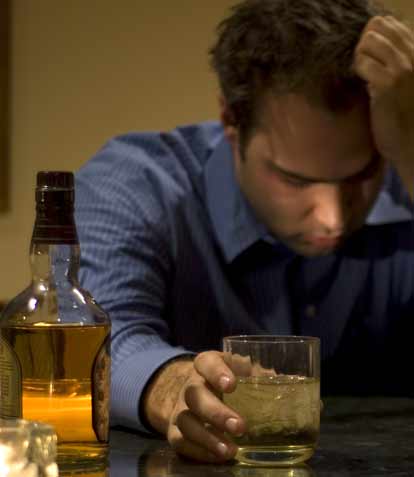  A man at a counter with a bottle of Scotch needing alcohol treatment services