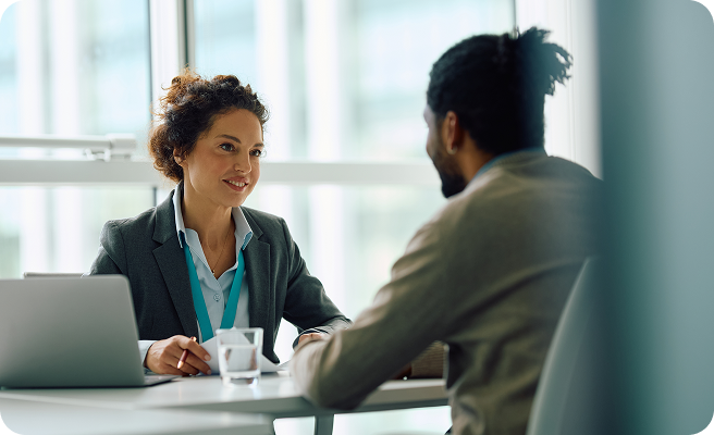 A woman talking to a man at her desk